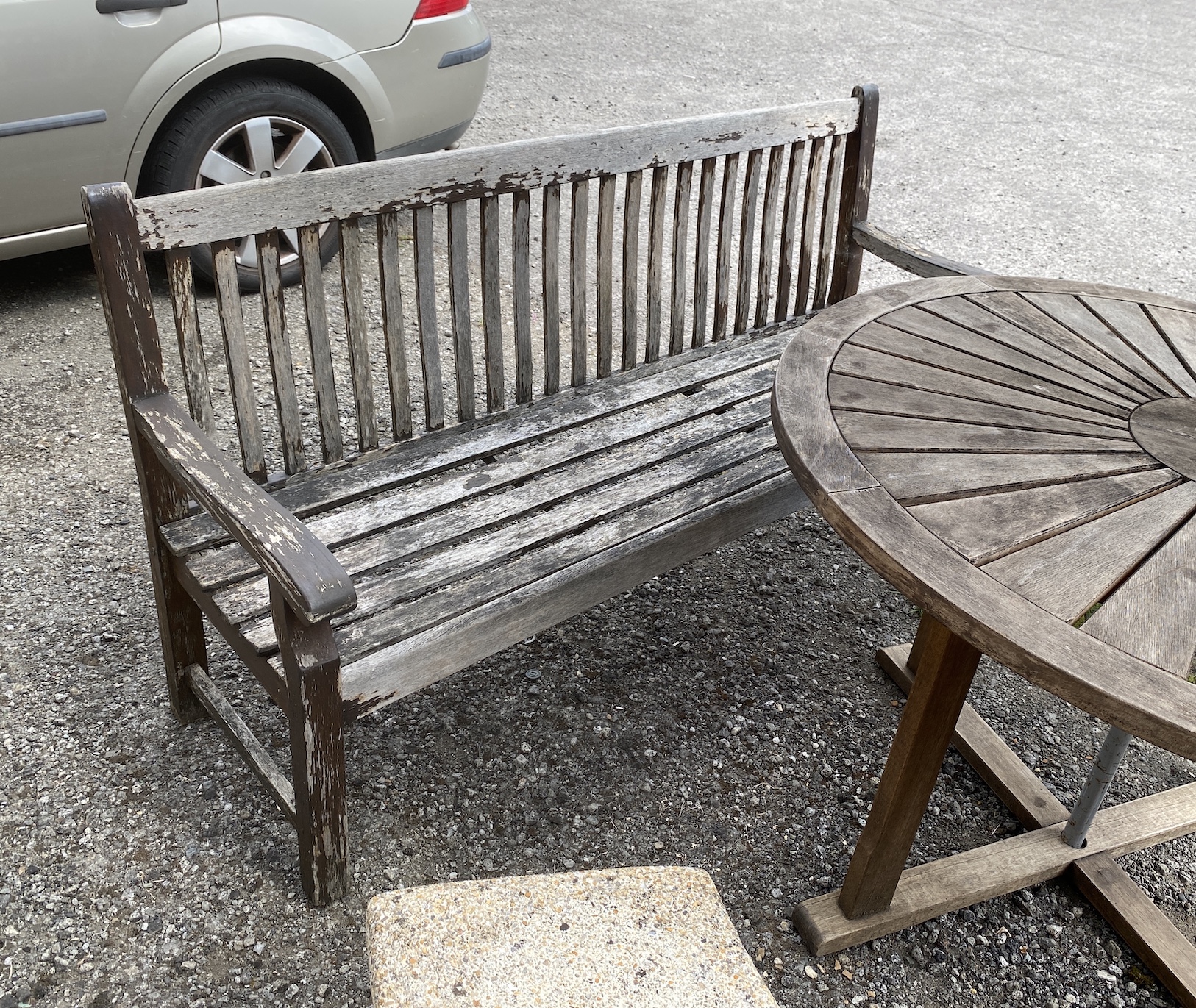 A circular weathered teak garden table, diameter 122cm, height 75cm parasol and bench
